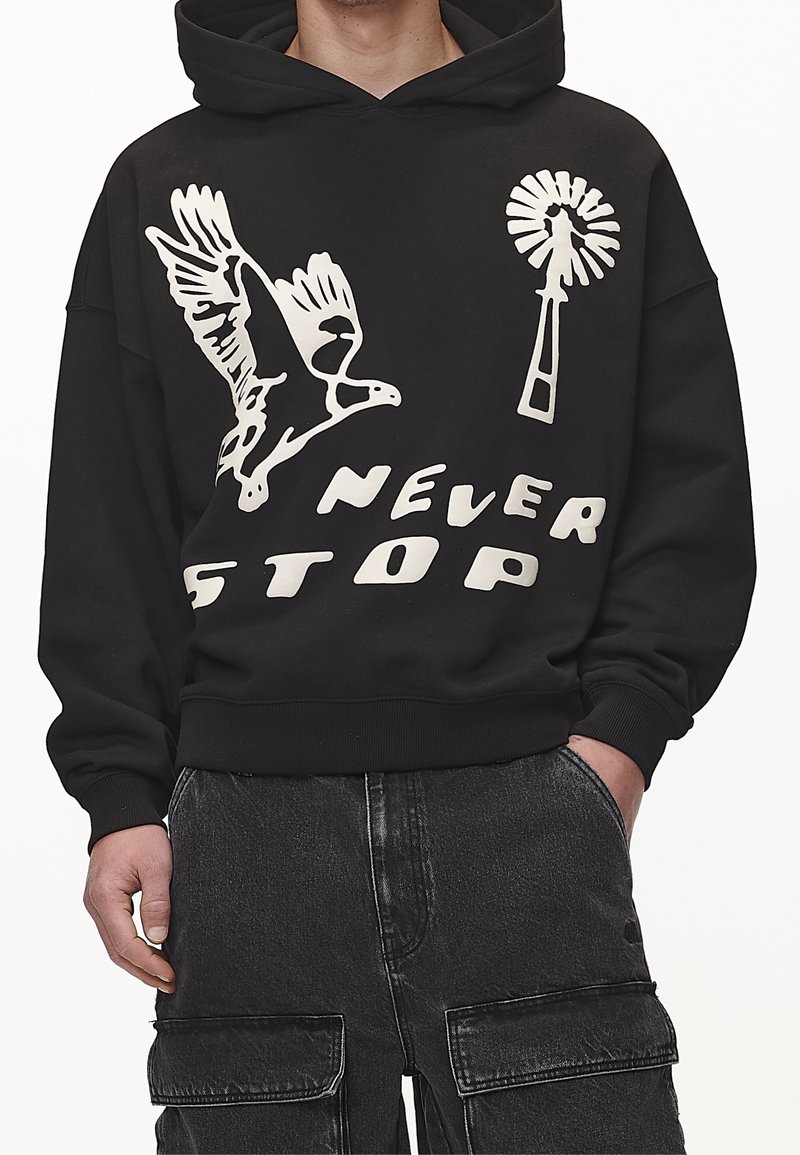 Zwarte hoodie met een wit grafisch ontwerp van een vogel, een paardebloem en de tekst "NEVER STOP." Materiaal lijkt zacht met een ontspannen pasvorm.