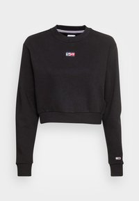 Sudadera negra recortada con mangas largas, puños y dobladillo acanalados, que presenta un pequeño logotipo rectangular rojo, blanco y azul en el pecho y en la manga.