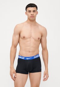Zwarte Nike boxershorts met een blauwe elastieken tailleband met het Nike-logo. Het materiaal is soepel en aansluitend, ontworpen voor comfort.