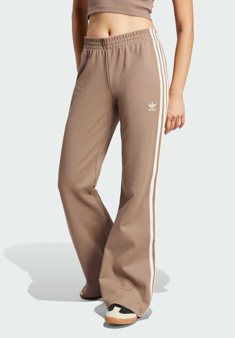 Bruna utsvängda sweatpants gjorda av mjukt material med vita sidostrickor, utrustade med resårmidja och en liten logo på höften.