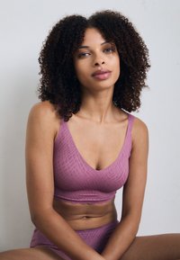 Light purple bralette with a textured pattern, soft fabric, and a v-neck design, paired with a matching bottom. Smooth edges, minimalistic style.