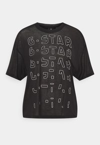 Černé oversized tričko s krátkým rukávem a kulatým výstřihem, na kterém jsou bíle konturované abstraktní písmena tvořící vzor "G-STAR" na přední straně.