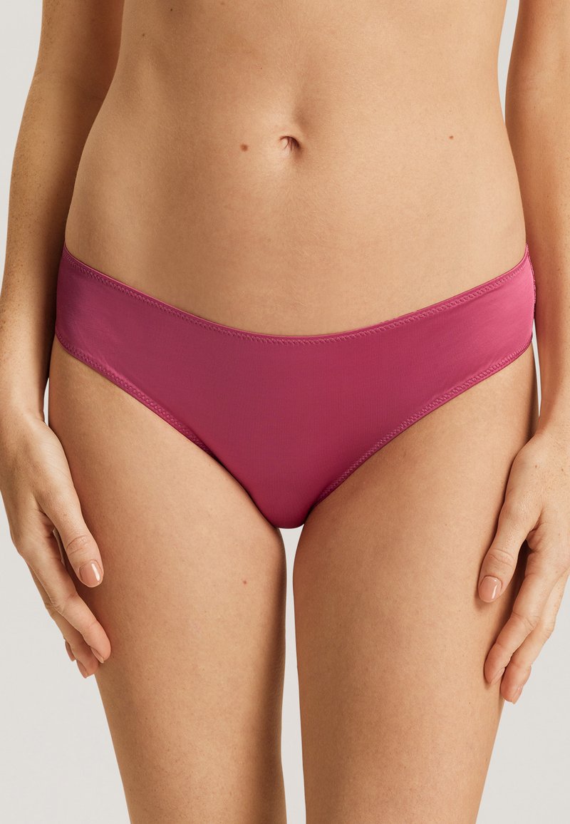 Parte inferior de bikini rosa hecha de un tejido suave, con un corte bajo y bordes suaves. Diseño simple sin adornos ni patrones.