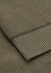 Tessuto a coste verde oliva con fine trama. Presenta un bordo cucito con cura e una superficie liscia, che enfatizza le linee orizzontali.