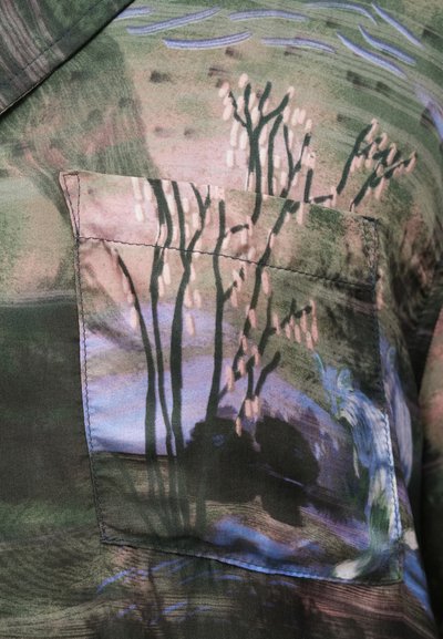 Μεταξωτό μπλουζάκι με τσέπη που διαθέτει πολύχρωμο σχέδιο τοπίο, συμπεριλαμβανομένων δέντρων και νερού, σε αποχρώσεις του πράσινου, μπλε και ροζ.