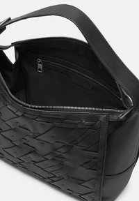 Czarna pleciona skórzana torba z zamkiem, z gładkim wnętrzem i małą kieszonką na zamek, prezentująca skomplikowane rzemiosło.