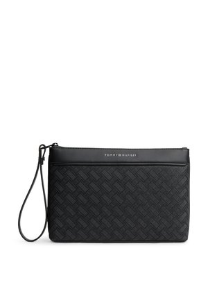 Schwarze Tommy Hilfiger Handgelenktasche mit strukturiertem gewebtem Muster und einem Riemen auf der linken Seite.