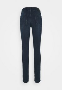 Mørkeblå skinny jeans med en glatt tekstur, midjehøyde, to baklommer og minimal søm. Ingen synlig maskinvares eller mønstre.