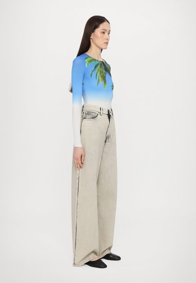 Long-sleeve bodysuit with palm tree print on a blue gradient, paired with high-waisted, oversized light gray denim jeans. Black flat shoes.