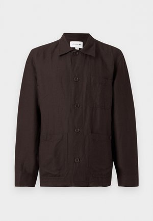 Tumepruun nööpidega jakk kraega, rinnatasku ja kahe alumise esistaskuga heledal ühtlasel taustal.