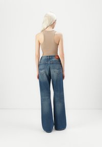 Brede denim jeans in donkerblauw met een vervaagde afwerking, met een logopatch op de achterste tailleband en twee achterzakken.