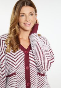 Cardigan in morbido maglione testurizzato con motivo a zigzag in bordeaux e bianco, con scollatura a V e quattro bottoni sul davanti.