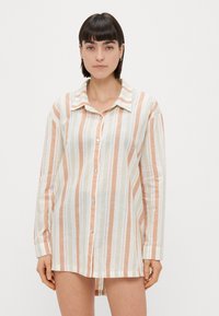 Knoop-overhemd met lange mouwen en verticale strepen in pastel perzik, groen en wit. Zachte stof, klassieke kraag en een ontspannen pasvorm.