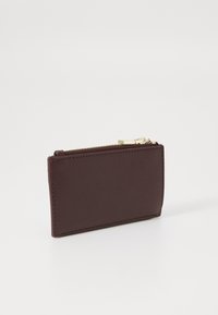 Portofel cardholder din piele maro închis, cu fermoar auriu, prezentat în poziție verticală pe fundal alb.