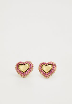 Guldtonade hjärtformade örhängen med rosa ädelstensdetaljer och ingraverat "GUESS" i mitten, med en texturerad kant.
