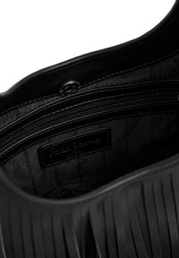 Must käekoti sisemus, kus on sile kangast vooder, tõmblukuga tasku ja etikett. Välispinnal on vertikaalsed voldid.