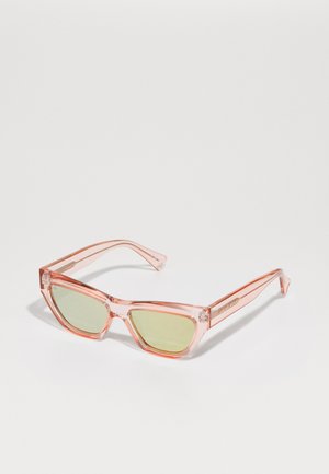 Roze transparante zonnebril met groen getinte lenzen, hoekige cat-eye vorm en heldere zijkanten. Voorzien van dunne tempelarmen.