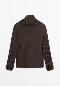 Chemise marron à manches longues avec une texture plissée, un col à volants et des poignets. Présente des coutures verticales et une coupe ample.
