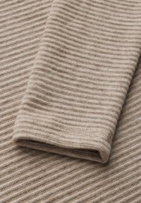 Tessuto a coste beige con una texture morbida, caratterizzato da pieghe sovrapposte e una finitura liscia. Strisce scorrono orizzontalmente.