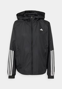 Veste noire à capuche zippée avec poignets élastiques, trois bandes blanches sur les manches et un petit logo triangulaire blanc sur la poitrine.