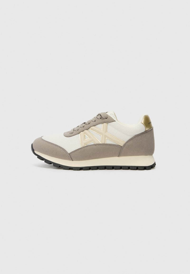 Sneakers con tomaia in rete crema, accenti in suede taupe e dettagli dorati sul tallone. Presentano una punta rotonda e suola in gomma nera testurizzata.