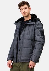 Chaqueta de plumas gris con un collar de pelo sintético, botones a presión, textura acolchada y bolsillos laterales. Incluye un parche con el logo en la manga.