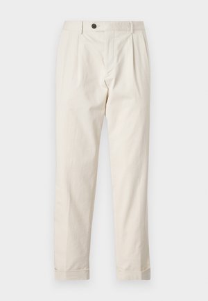 Pantalons crème avec une coupe ajustée, présentant une fermeture à un bouton, un devant plissé et des ourlets à revers. Fabriqués en tissu léger.