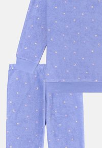 Purple fleece matching set featuring a long-sleeve top and pants, adorned with small gold moons and pink stars in a scattered pattern.
