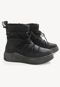 Bottines noires avec une doublure intérieure douce, un dessus rembourré, des lacets ajustables et une semelle en caoutchouc texturée avec des rainures horizontales.