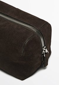 Prodotto in camoscio marrone, questo beauty case ha una forma rettangolare e una base piatta. Presenta una cerniera in metallo argentato e dettagli in pelle nera con cuciture.