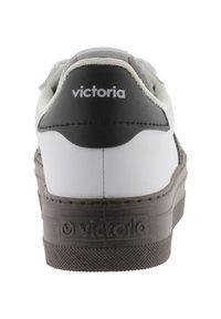 Sneaker bianco con un contrafforte nero, dettagli grigi e suola in gomma. Presenta il logo "victoria" sul tallone e una superficie testurizzata.