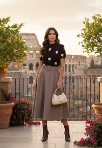 Czarny top z krótkim rękawem z różowym haftem kwiatowym, beżowa spódnica o wysokim stanie, brązowe botki na obcasie i mała kremowa torebka.