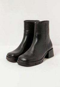 Botas de tobillo de piel negra con punta redonda, tacón de bloque y un sutil pespunte lateral. Textura suave con un diseño elegante y suela de goma.
