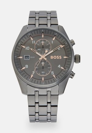 Montre analogique avec un cadran gris foncé, des accents en or rose, des sous-cadrans chronographes et un bracelet en acier inoxydable. Comprend un guichet de date.