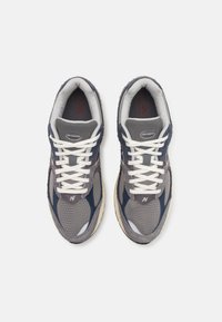 Šedé a námořnické tenisky z prodyšného materiálu a z broušené kůže, bílé tkaničky, vypolstrovaný límec a viditelné logo. Mírně opotřebovaná béžová podešev.