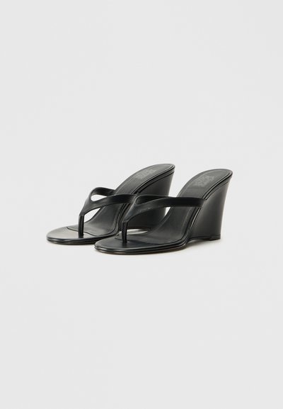 Čierne wedges sandále s hladkým koženým povrchom, otvorenou špičkou a popruhom v štýle tanga. Opätok je vysoký a uhlový, čím pridáva moderný dizajn.