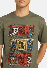 Green shirt with vintage-style train cars featuring a dog, skeleton conductor, and cartoon dog with the words "Ride the Rails."