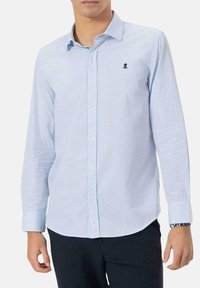 Camisa de manga larga a cuadros azules y blancos, con cuello abotonado, que presenta un pequeño logotipo en el pecho y puños con un patrón en contraste.