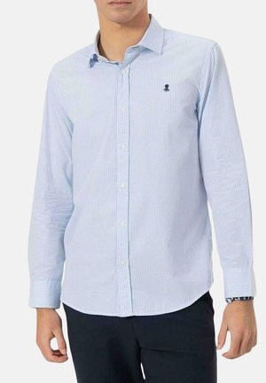Camisa de manga larga a cuadros azules y blancos, con cuello abotonado, que presenta un pequeño logotipo en el pecho y puños con un patrón en contraste.