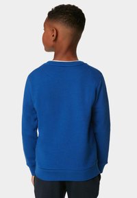 Felpa blu con collo a giro, maniche lunghe e polsini a coste. Tessuto liscio con una vestibilità comoda, caratterizzata da un design di colore unito.