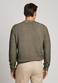Oliven grøn, ribbet sweater med rund halsudskæring, lange ærmer og struktureret stof. Matchet med lyse beige bukser.