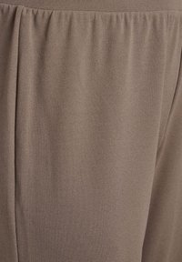 Tessuto marrone con una texture liscia e una leggera lucentezza. Presenta pieghe per un maggior flusso e caduta, adatto per capi d'abbigliamento o accessori.