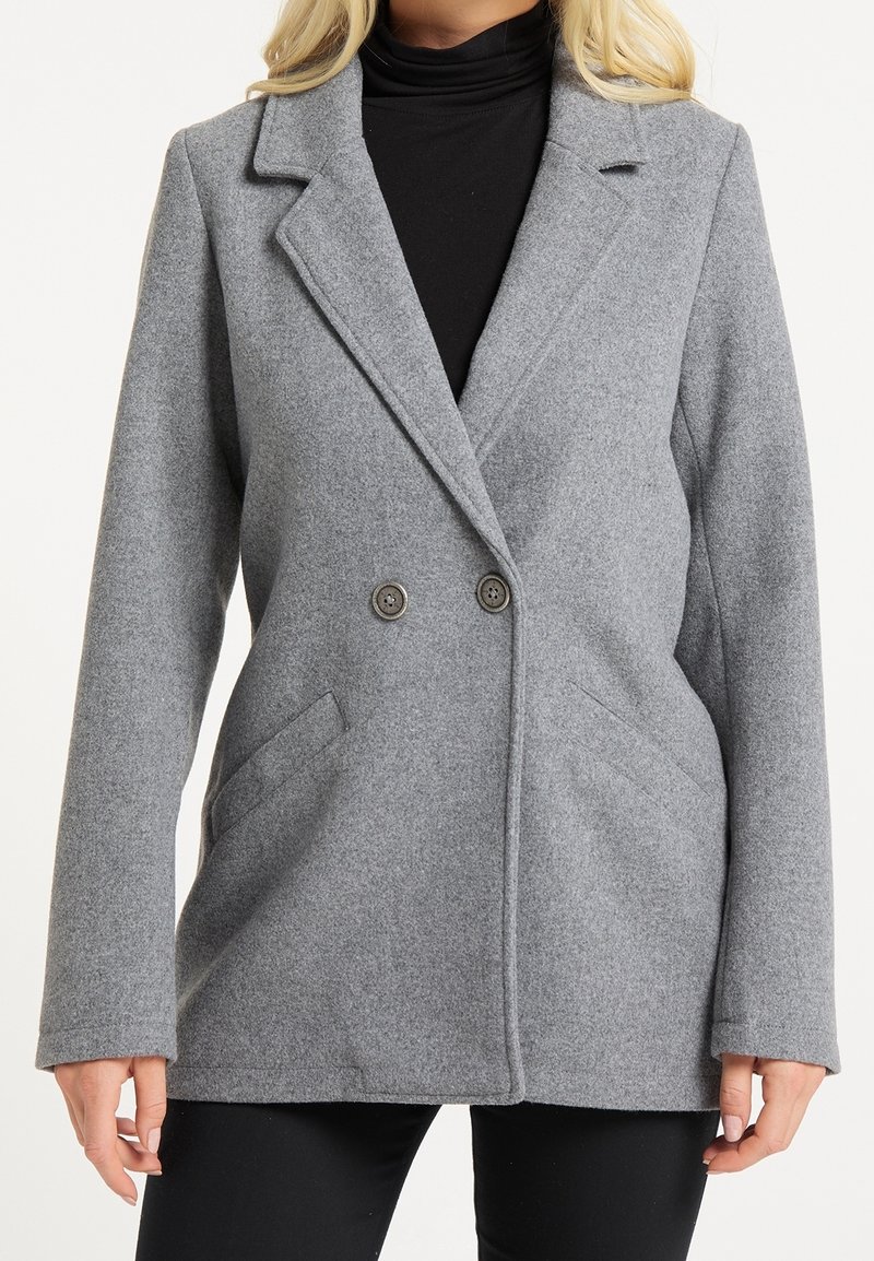 Manteau en mélange de laine gris avec un devant à double boutonnage, des revers crantés, deux poches latérales et des accents de boutons. Texture lisse et coupe ajustée.