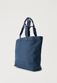 Meresinine käekott kahekordsete õlarihmadega, kangast riba peene Lacoste'i logoga ülaääres.