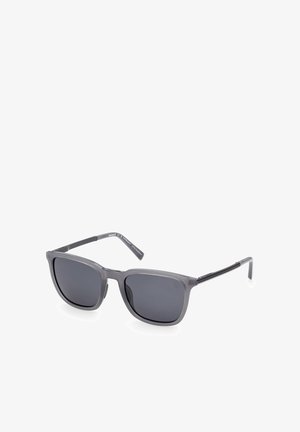Graue rechteckige Sonnenbrille mit dunkel getönten Gläsern und dünnen schwarzen Bügeln, leicht schräg auf weißem Hintergrund gezeigt.