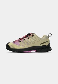 Scarpa da trail beige chiaro con dettagli rosa, tomaia testurizzata, punta nera resistente e suola spessa nera con sottopiede rosa.