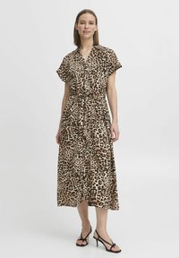 Maxiklänning med leopardmönster i lätt tyg, med korta ärmar, midja med dragsko och flödande silhuett. Svarta remsandaler.