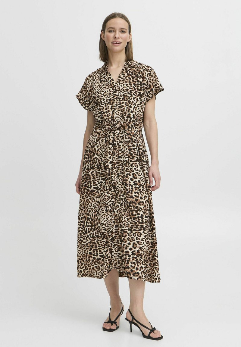 Rochie maxi cu imprimeu leopard dintr-un material ușor, cu mâneci scurte, talie strânsă și o siluetă fluidă. Sandale negre cu bretele.