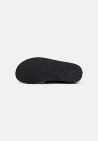 Black shoe sole with a textured rubber surface, rounded shape, and smooth edges, designed for grip and durability.