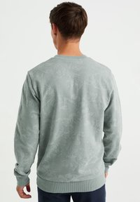 Ljusgrön sweatshirt med präglat blommönster, rundhalsad, ribbade ärmslut och nederkant, tillverkad av mjukt och texturerat tyg.